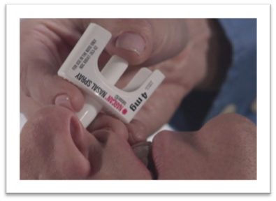 Close-up of a Narcan nasal spray device being administered to a person's nostril.